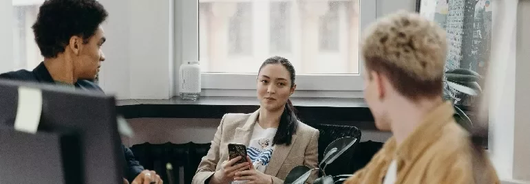 Three people having a discussion in an office.